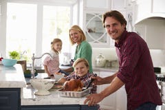 Family Preparing Roast Turkey Meal In Kitchen Together stock image Family Preparing Roast Turkey Meal In Kitchen Together stock image