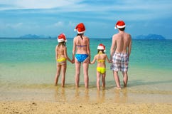Family vacation on Christmas and New Year holidays, happy parents and children in santa hats have fun on beach Stock Images Family vacation on Christmas and New Year holidays, happy parents and children in santa hats have fun on beach Stock Images
