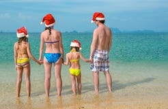 Family vacation on Christmas and New Year holidays, happy parents and children in santa hats have fun on beach Royalty Free Stock Photo Family vacation on Christmas and New Year holidays, happy parents and children in santa hats have fun on beach Royalty Free Stock Photo