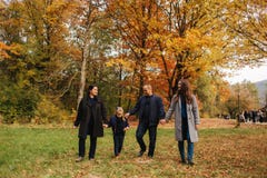 Family walking in an autumn forest with fallen leaves. Mother father and two daughters in the park royalty free stock photos Family walking in an autumn forest with fallen leaves. Mother father and two daughters in the park royalty free stock photos