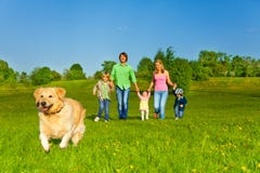 Family walks with running dog in park