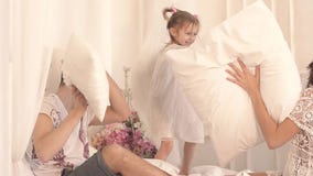 Família de três feliz: mãe, pai e filha tendo uma luta de descanso na cama vídeos de arquivo Família de três feliz: mãe, pai e filha tendo uma luta de descanso na cama vídeos de arquivo