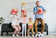 família entusiasmado que guarda caixas e que joga a pipoca fotografia de stock família entusiasmado que guarda caixas e que joga a pipoca fotografia de stock
