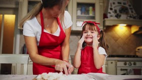 Família feliz na mamã e na filha da cozinha na cozinha que joga com farinha para ter o divertimento e moldar os rissóis no filme Família feliz na mamã e na filha da cozinha na cozinha que joga com farinha para ter o divertimento e moldar os rissóis no filme