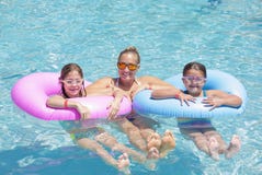 Família feliz que joga nos tubos infláveis em uma piscina em um dia ensolarado Imagem de Stock Royalty Free Família feliz que joga nos tubos infláveis em uma piscina em um dia ensolarado Imagem de Stock Royalty Free