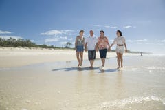 Família que anda nas mãos da terra arrendada da praia Imagem de Stock Royalty Free Família que anda nas mãos da terra arrendada da praia Imagem de Stock Royalty Free