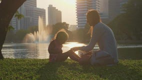 Família que tem o divertimento no parque com lago e arranha-céus no fundo filme Família que tem o divertimento no parque com lago e arranha-céus no fundo filme
