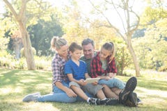 Família que usa a tabuleta digital no parque Imagens de Stock Família que usa a tabuleta digital no parque Imagens de Stock