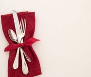 Fancy Christmas or Valentines Day Table Place Setting with cloth red napkin, silverware, and bow on creamy white tablecloth backgr