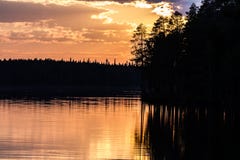 Fantastische zonsondergang op het meer, donker pijnboombos die in het kalme water nadenken royalty-vrije stock afbeeldingen Fantastische zonsondergang op het meer, donker pijnboombos die in het kalme water nadenken royalty-vrije stock afbeeldingen