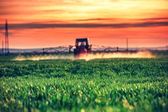 Farming tractor plowing and spraying on field by the sunset royalty free stock photography Farming tractor plowing and spraying on field by the sunset royalty free stock photography