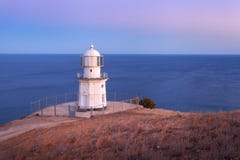 Faro blanco hermoso en la costa costa del océano en la puesta del sol Paisaje imagen de archivo Faro blanco hermoso en la costa costa del océano en la puesta del sol Paisaje imagen de archivo