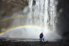 Farsa och unge under regnbågen på foten av Skogafoss den tunga vattenfallet i Island royaltyfri foto Farsa och unge under regnbågen på foten av Skogafoss den tunga vattenfallet i Island royaltyfri foto
