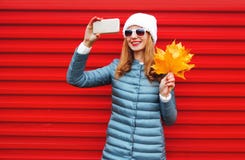 Fashion autumn smiling woman takes a picture self portrait on a smartphone stock image Fashion autumn smiling woman takes a picture self portrait on a smartphone stock image