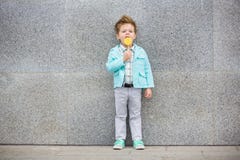 Fashion kid with lollipop near gray wall stock photography Fashion kid with lollipop near gray wall stock photography