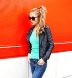 Fashion beautiful woman in sunglasses black rock jacket walking at city over red. Background Royalty Free Stock Photos Fashion beautiful woman in sunglasses black rock jacket walking at city over red. Background Royalty Free Stock Photos
