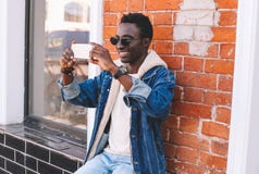 Fashion cheerful smiling african man taking selfie by smartphone or having video call royalty free stock photo Fashion cheerful smiling african man taking selfie by smartphone or having video call royalty free stock photo