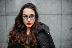 Fashion consept: beatiful young girl with long hair, glasses, red lips standing near modern wall wearing in green suit and grey je royalty free stock photography Fashion consept: beatiful young girl with long hair, glasses, red lips standing near modern wall wearing in green suit and grey je royalty free stock photography