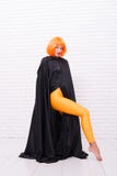 Fashion is her life. Fashion model wearing orange wig hair and black robe on white brickwall. Sexy girl with fashion stock photos Fashion is her life. Fashion model wearing orange wig hair and black robe on white brickwall. Sexy girl with fashion stock photos