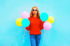 Fashion woman does an air kiss with colorful balloons on blue Stock Photo Fashion woman does an air kiss with colorful balloons on blue Stock Photo