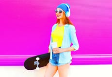 Fashion young woman with skateboard and coffee cup listens to music Stock Photography Fashion young woman with skateboard and coffee cup listens to music Stock Photography