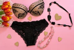 Fashionable black lace woman lingerie composition with red tulip flowers black and pink necklace and wooden hearts on pink stock photo Fashionable black lace woman lingerie composition with red tulip flowers black and pink necklace and wooden hearts on pink stock photo