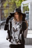 Fashionable girl dressed in black trousers, a stylish gray shirt and sweater and in a black hat with wide brim walks in royalty free stock photography Fashionable girl dressed in black trousers, a stylish gray shirt and sweater and in a black hat with wide brim walks in royalty free stock photography