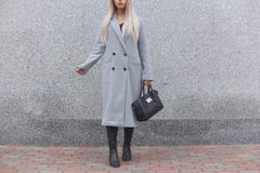 Fashionable woman posing outdoor, holding black leather bag, wearing stylish boots, elegant coat. Female fashion concept Stock Images Fashionable woman posing outdoor, holding black leather bag, wearing stylish boots, elegant coat. Female fashion concept Stock Images