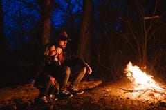Father and his little son sitting together on the logs in front of a fire at the night. The hike in the forest. royalty free stock photography Father and his little son sitting together on the logs in front of a fire at the night. The hike in the forest. royalty free stock photography
