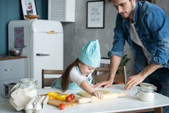 Father and little daughter baking pastries. Family having fun in kitchen and getting ready for a party. royalty free stock image Father and little daughter baking pastries. Family having fun in kitchen and getting ready for a party. royalty free stock image