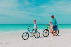 Father with little son and daughter biking on beach stock images Father with little son and daughter biking on beach stock images