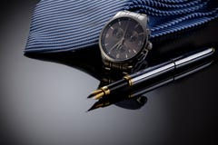 Father& x27;s Day or business concept image. Elegant man& x27;s watch, fountain pen and blue tie on black gradient background. Royalty Free Stock Photography Father& x27;s Day or business concept image. Elegant man& x27;s watch, fountain pen and blue tie on black gradient background. Royalty Free Stock Photography