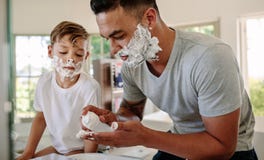 Father and son applying shaving foam on their faces royalty free stock photography Father and son applying shaving foam on their faces royalty free stock photography