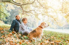 Father, son and beagle dog sitting in autumn park, warm indian s royalty free stock image Father, son and beagle dog sitting in autumn park, warm indian s royalty free stock image