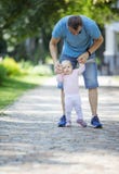 Father supporting baby daughter and helping her make first steps royalty free stock images Father supporting baby daughter and helping her make first steps royalty free stock images