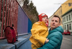 Father taking his little daughter with Down syndrome to school, outdoors in street.