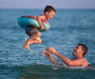 Father throws up his son in an inflatable circle under the sea Royalty Free Stock Images Father throws up his son in an inflatable circle under the sea Royalty Free Stock Images