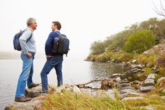 Father and young adult son standing by a lake stock image Father and young adult son standing by a lake stock image