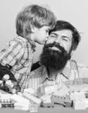 Fathers day. Father and son have fun with bricks. Bearded hipster and boy play together. Dad and child build of plastic royalty free stock image Fathers day. Father and son have fun with bricks. Bearded hipster and boy play together. Dad and child build of plastic royalty free stock image