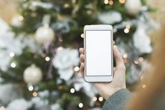 Faux du smartphone dans la main de la fille sur le fond de l'arbre de Noël avec une décoration de fête image stock Faux du smartphone dans la main de la fille sur le fond de l'arbre de Noël avec une décoration de fête image stock