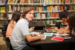 Fazendo trabalhos de casa na biblioteca imagem de stock Fazendo trabalhos de casa na biblioteca imagem de stock