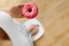 Faça dieta o conceito Mulher na escala que guarda a filhós Perda de peso dieting foto de stock royalty free Faça dieta o conceito Mulher na escala que guarda a filhós Perda de peso dieting foto de stock royalty free