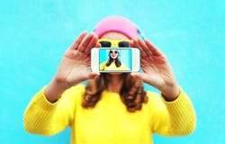Façonnez la fille fraîche prenant l'autoportrait de photo sur le smartphone au-dessus du fond blanc utilisant les vêtements et le images stock Façonnez la fille fraîche prenant l'autoportrait de photo sur le smartphone au-dessus du fond blanc utilisant les vêtements et le images stock