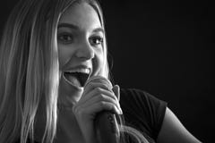 Façonnez le portrait d'une femme chantant avec un microphone sans fil photographie stock Façonnez le portrait d'une femme chantant avec un microphone sans fil photographie stock