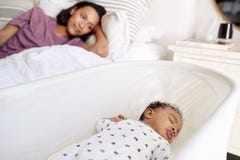 Feche acima da mãe adulta nova que encontra-se em sua cama que olha para baixo em seu bebê idoso de três meses que dorme em seu b imagens de stock royalty free Feche acima da mãe adulta nova que encontra-se em sua cama que olha para baixo em seu bebê idoso de três meses que dorme em seu b imagens de stock royalty free