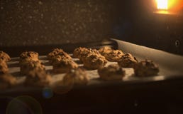 Feche acima das cookies dos pedaços de chocolate em uma bandeja do cozimento no forno, na imagem vermelha e marrom filtrada do vi imagem de stock royalty free Feche acima das cookies dos pedaços de chocolate em uma bandeja do cozimento no forno, na imagem vermelha e marrom filtrada do vi imagem de stock royalty free
