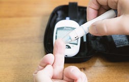 Feche acima das mãos usando a lanceta no dedo para verificar o sangue alto SU fotos de stock Feche acima das mãos usando a lanceta no dedo para verificar o sangue alto SU fotos de stock