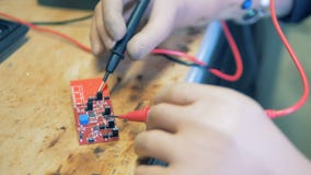 Feche acima de um microscheme que obtém soldado pelas mãos artificiais do ` s da pessoa Feche acima de um microscheme que obtém soldado pelas mãos artificiais do ` s da pessoa