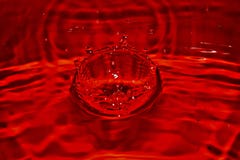 Feche acima do respingo vermelho da gota do SANGUE no sangue com fundo alaranjado Textura e projeto de superfície rippled brilhan imagens de stock Feche acima do respingo vermelho da gota do SANGUE no sangue com fundo alaranjado Textura e projeto de superfície rippled brilhan imagens de stock