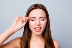Feche acima do retrato da jovem mulher que arranca as sobrancelhas com pinça imagem de stock Feche acima do retrato da jovem mulher que arranca as sobrancelhas com pinça imagem de stock